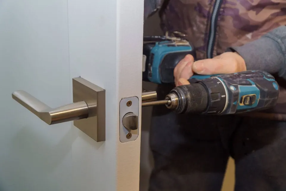A door handle and latch being installed on a white residential door